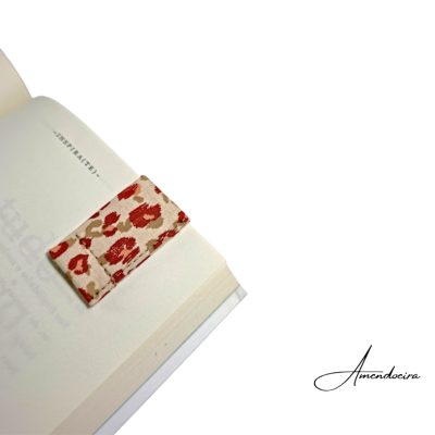Marcador de livros de tecido com padrão vermelho e castanho num livro aberto