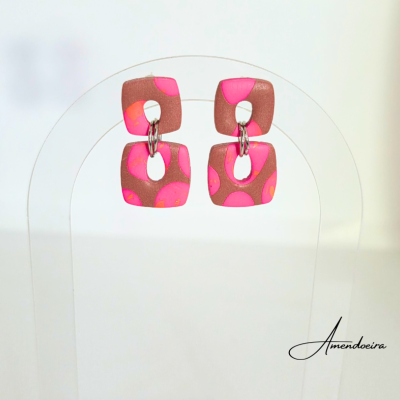 Brincos quadrados castanhos com manchas rosa fluorescente em suporte transparente