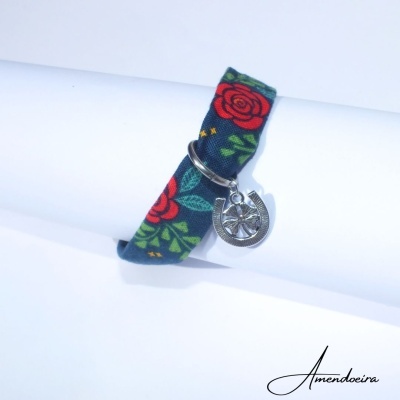 Pulseira em tecido azul com rosas vermelhas e pendente em metal prateado