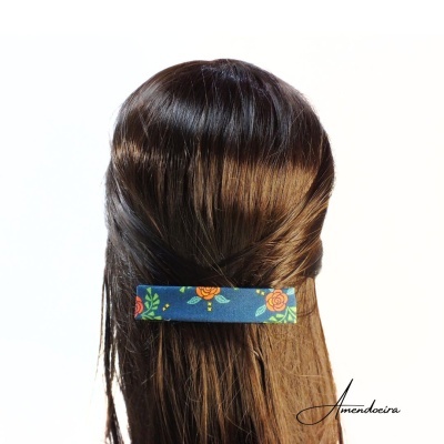 Prendedor de cabelo azul com flores numa cabeça de cabelo castanho