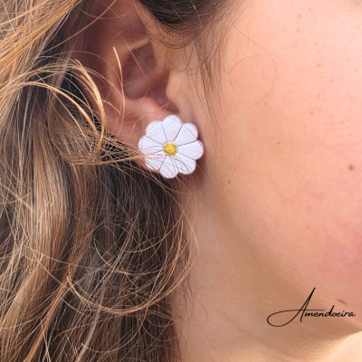 Brinco flor branco com centro amarelo no lóbulo da orelha