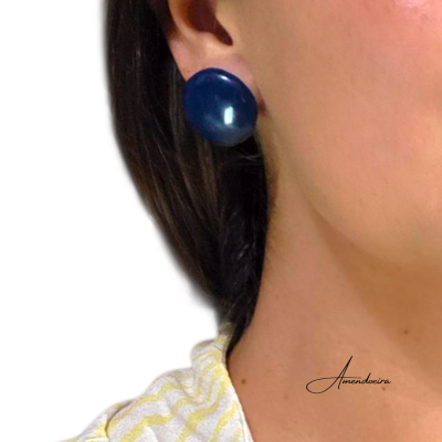 Brinco redondo azul escuro liso e brilhante numa orelha com camisa amarelo clara e branca