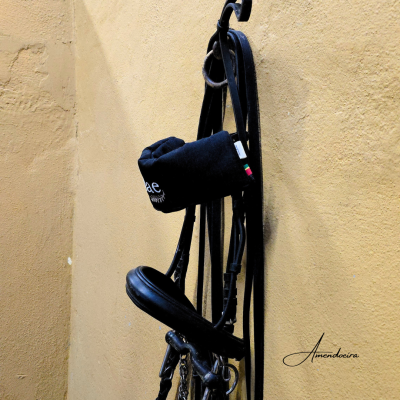 Cadeira de montar preta em couro pendurada numa parede amarela