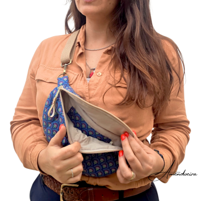 Bolsa tiracolo azul com padrão colorido e interior bege numa mulher com camisa castanha