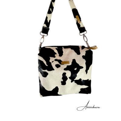 Mala quadrada preta e branca com alça removível e etiqueta de metal.