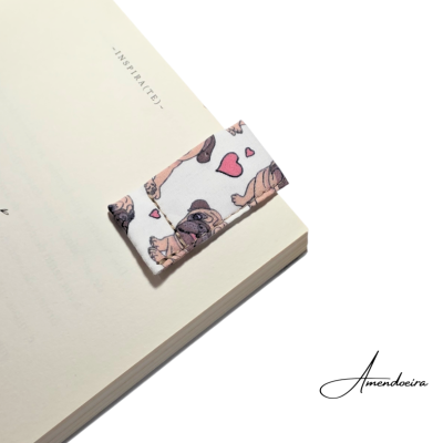 Marcador de livro em tecido com padrão de cães carlinhos e corações sobre livro aberto