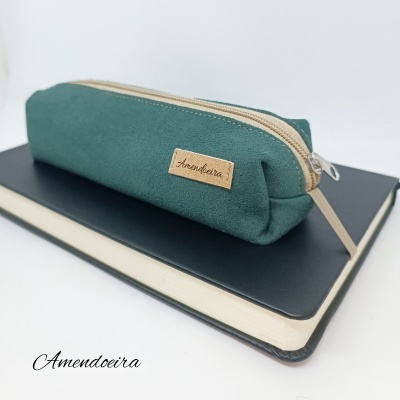 Estojo escolar verde escuro com fecho zip bege sobre caderno preto