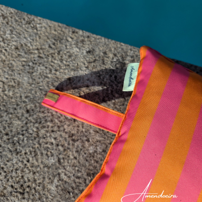Almofada laranja e rosa com riscas perto de piscina
