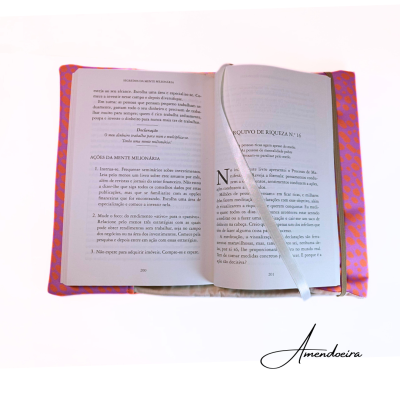 Livro aberto com capa rosa de tecido com bolinhas laranja e marcador branco