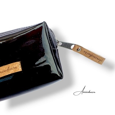 Necessaire preta brilhante com etiquetas castanhas com inscrição Amendeira