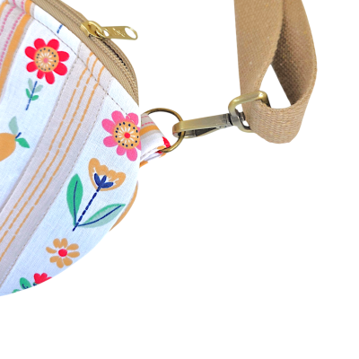 Bolsa com padrão floral, fecho dourado e alça bege.