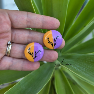 Par de brincos redondos laranja e roxo com desenho de ramo preto