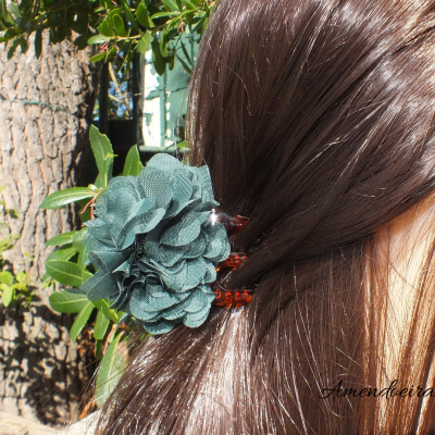 Grampo de cabelo com flor verde em cabelo castanho ao ar livre