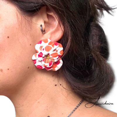Brincos florais coloridos grandes no ouvido de uma pessoa