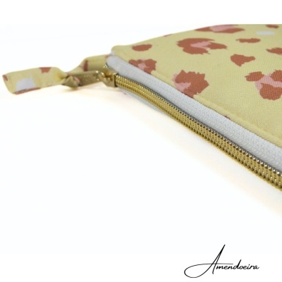 Estojo plano com padrão manchado castanho em fundo bege e fecho de correr dourado.