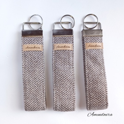 Três porta-chaves de tecido espinha de peixe cinza e branco com etiquetas de couro Amendoeira.