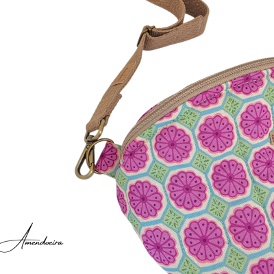 Bolsa tiracolo com padrão floral rosa, verde e azul e alça castanha.
