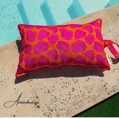 Almofada rosa e laranja com padrão animal junto à piscina