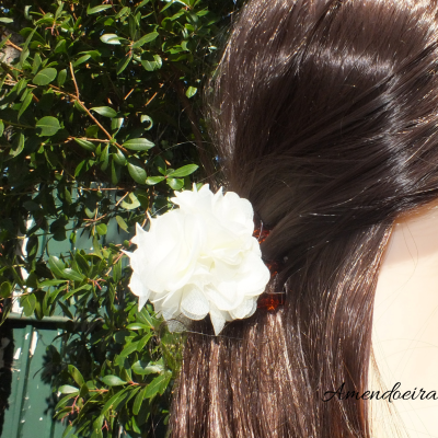 Grampo de cabelo com flor de tecido branca em cabelo castanho escuro.