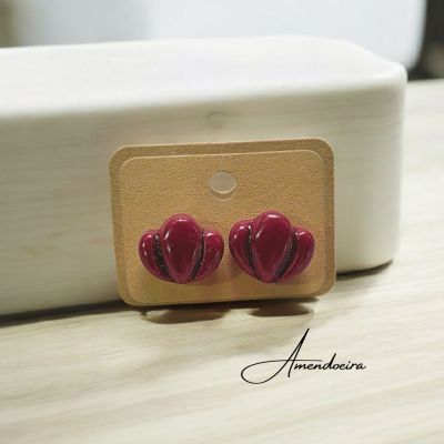 Brincos vermelhos em cartão castanho sobre mesa de madeira clara