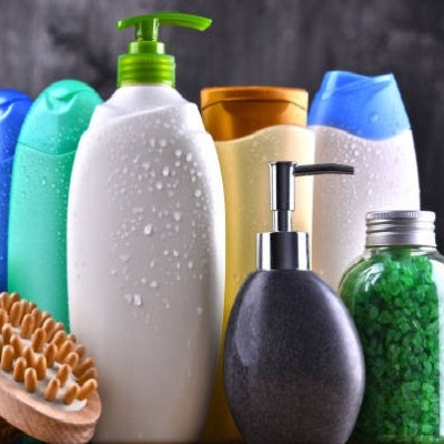 Frascos de produtos de cuidado pessoal com escova de madeira e toalhas em fundo escuro