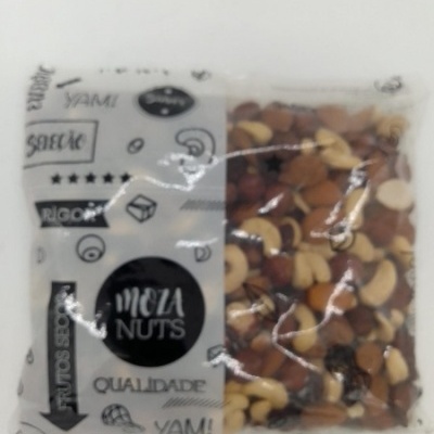Pacote transparente de frutos secos Meza Nuts com etiqueta branca e preta exibindo texto em português
