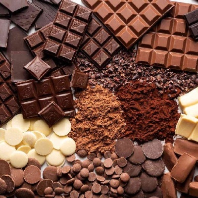 Várias barras e pedaços de chocolate em diferentes tons com gotas e pó de cacau