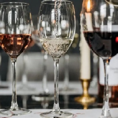 Cinco copos de vinho com diferentes vinhos sobre mesa escura