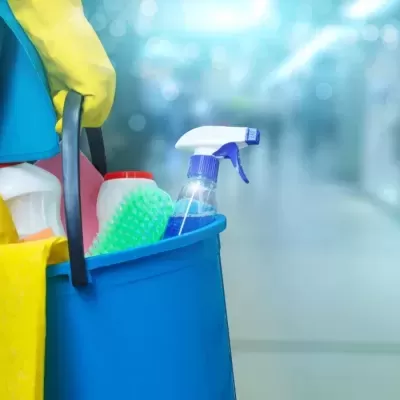 Balde azul com produtos e ferramentas de limpeza em ambiente interior desfocado