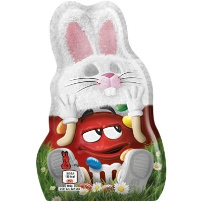 Embalagem de chocolate M&M's em forma de coelho rodeado por relva e flores