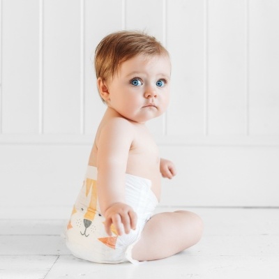 Bebé sentado com fralda descartável colorida num fundo branco