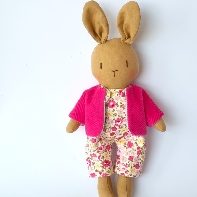 Boneco de peluche em forma de coelho com roupa floral e casaco rosa