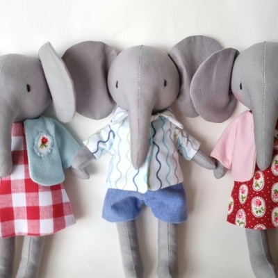 Três bonecos elefante de tecido com roupas coloridas