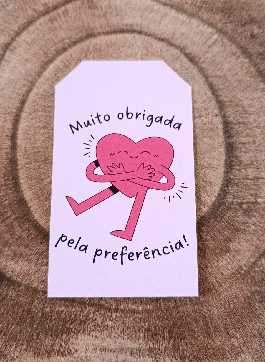 Etiqueta com coração cor-de-rosa e texto em português sobre superfície de madeira