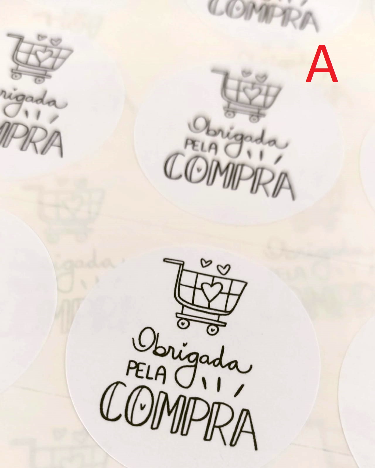 Etiquetas redondas brancas com texto Obrigada PELA COMPRA e carrinho de compras desenhado a preto