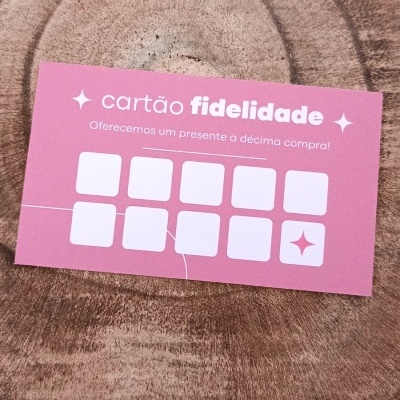 Cartão de fidelidade rosa com texto branco e quadrados para carimbos, usado para promoções.
