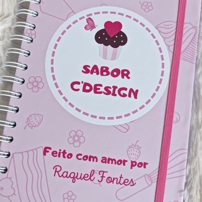 Caderno rosa com desenhos de cozinha e etiqueta com cupcake e texto sabor c'design