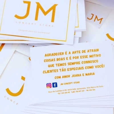 Cartões de visita e etiquetas JM Concept Store com texto em português e design branco e dourado.