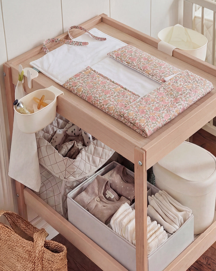 Mesa muda-fraldas de madeira com almofada floral cor-de-rosa e acessórios para bebé