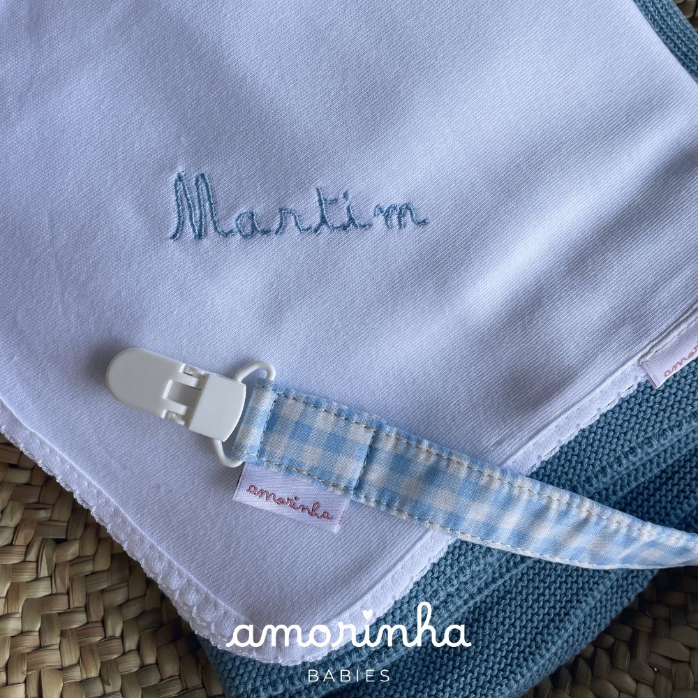 Babete branca bordada e suporte de chupeta azul com padrão xadrez