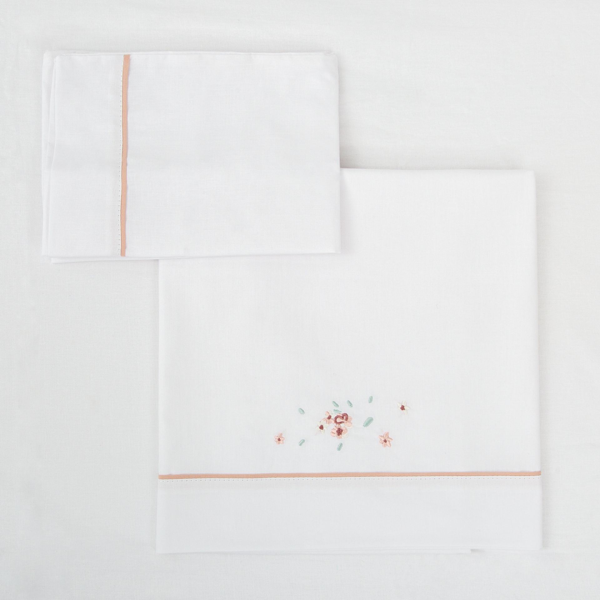 Jogo de cama branco com bordado floral e detalhe rosa