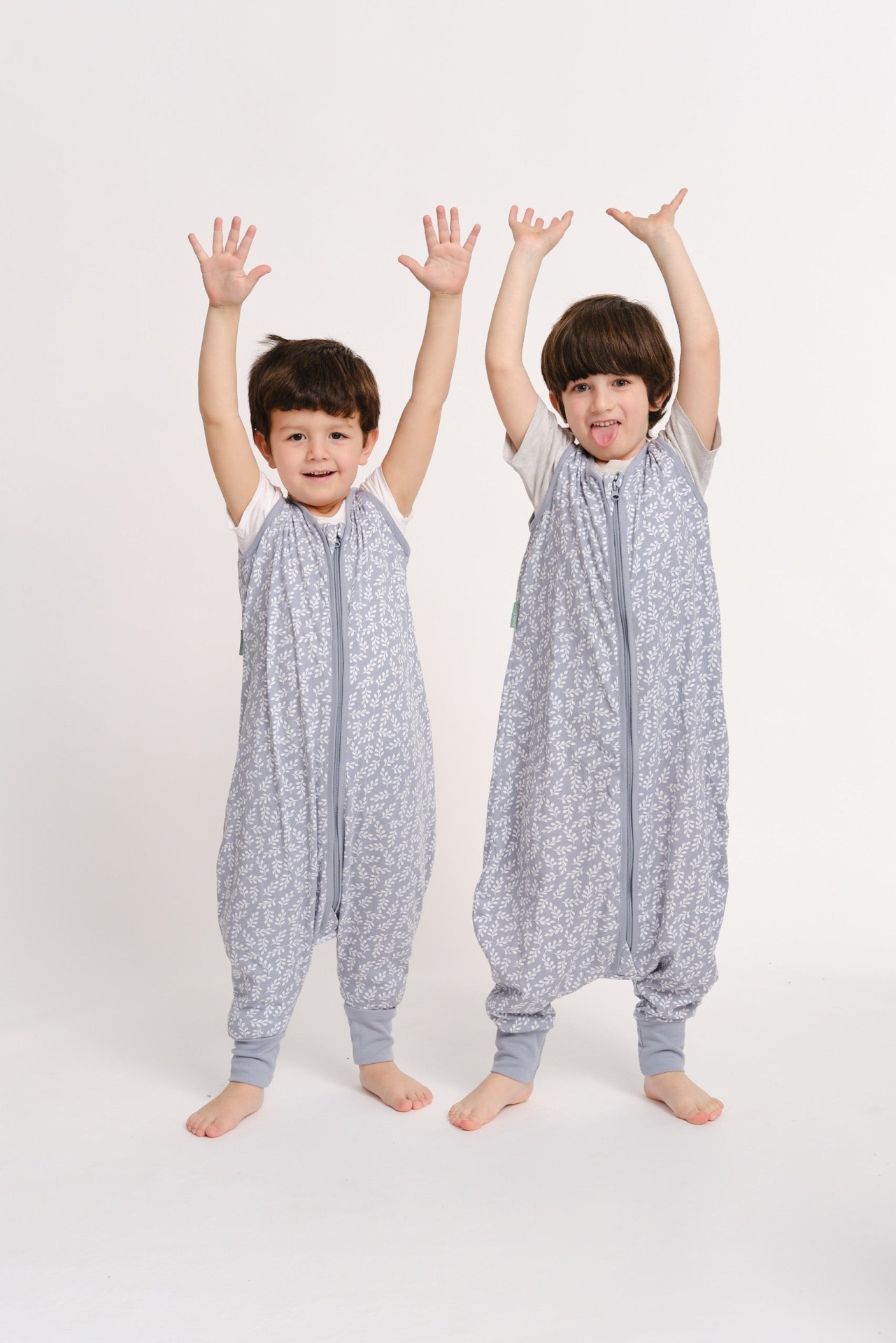 Dois meninos com macacões cinza claro com padrão branco em fundo branco