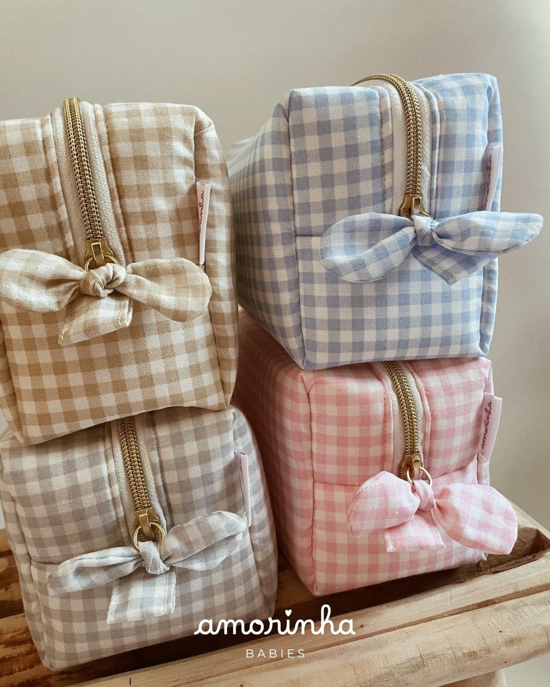 Bolsas quadradas de tecido xadrez em bege, azul, cinza e rosa com fecho dourado e laço.