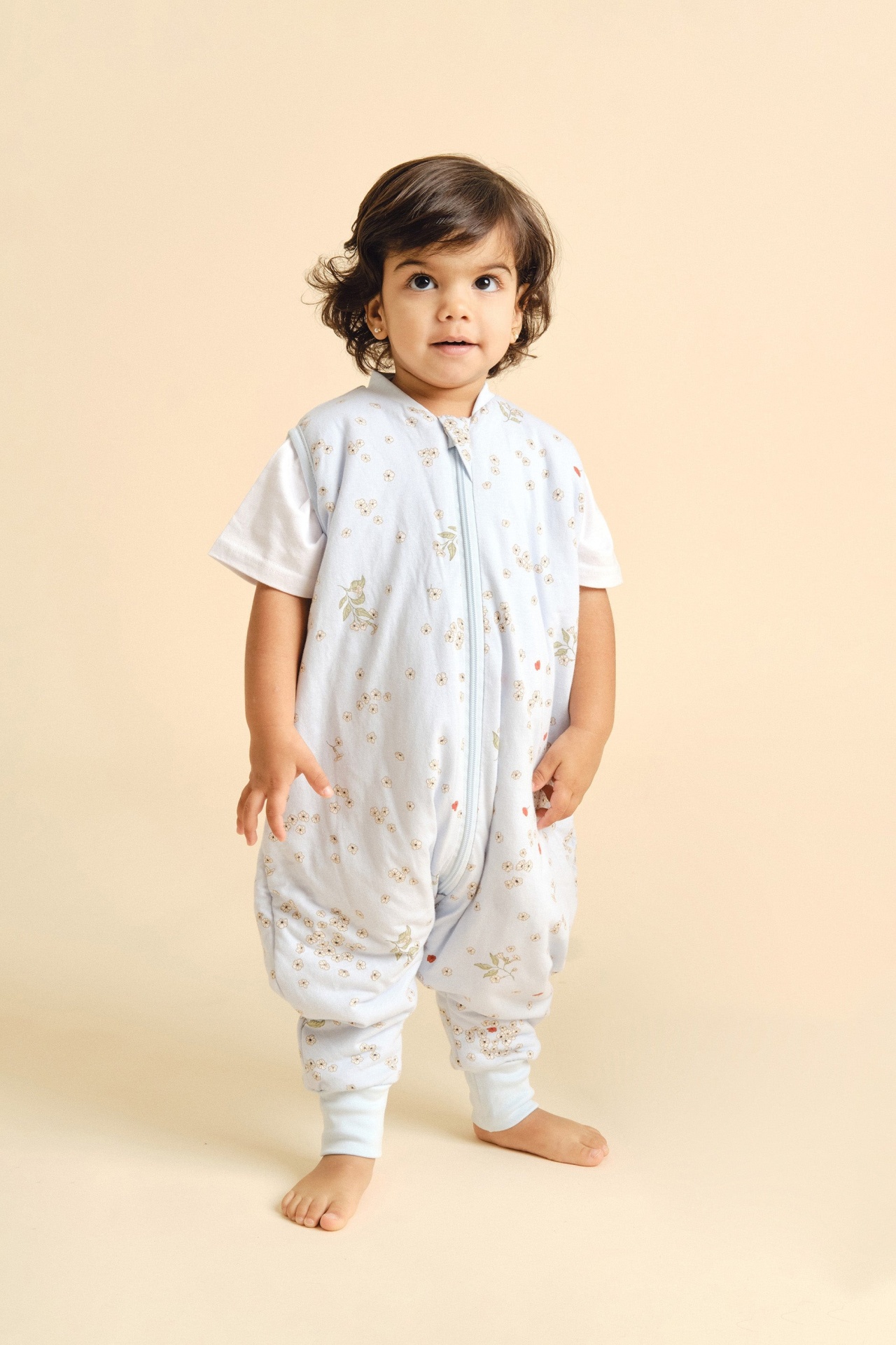 Criança com saco de dormir azul claro com padrão floral e camiseta branca