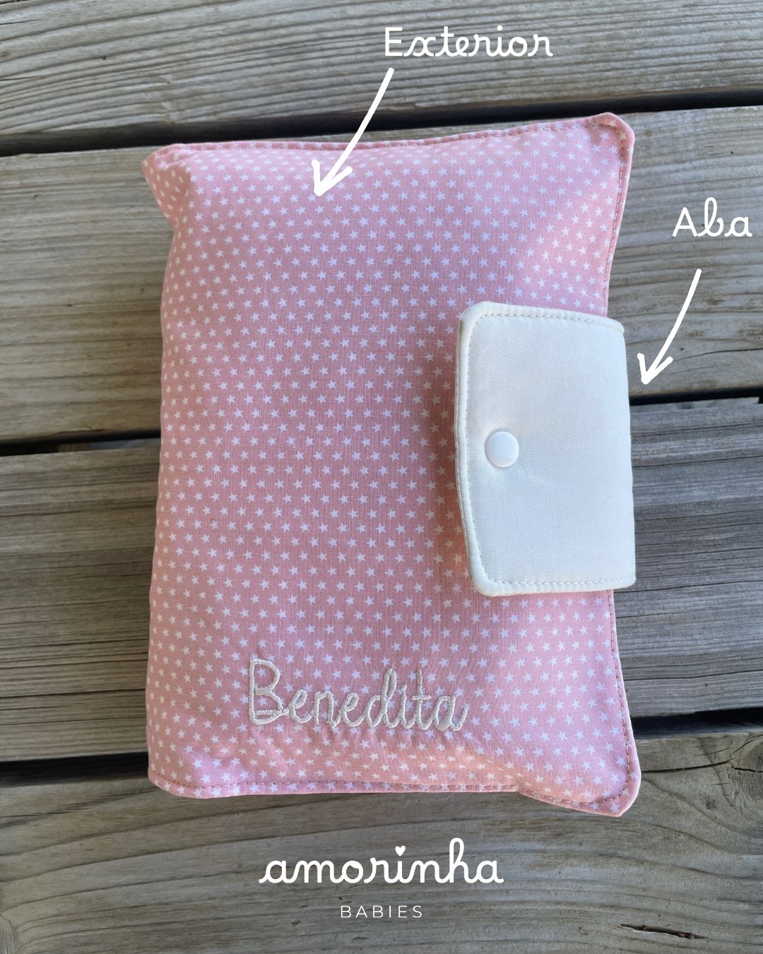 Capa rosa com estrelas brancas e fecho branco, com o nome Benedita bordado.