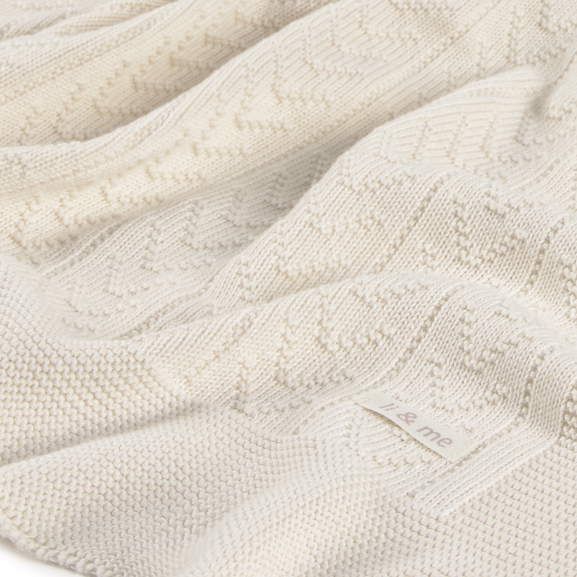 Tecido de malha branca com padrão texturizado e etiqueta i & me