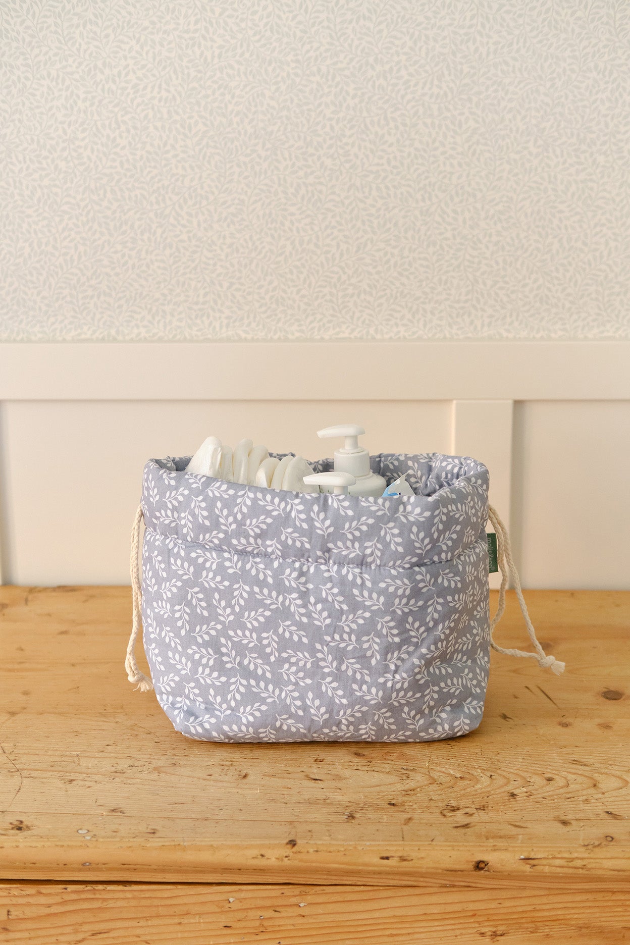 Organizador de tecido azul com padrão branco e dispensadores de produtos de higiene