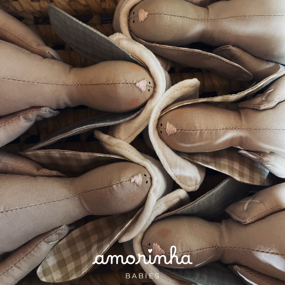 Bonecos de pano castanhos com orelhas xadrez e bege arrumados numa caixa.