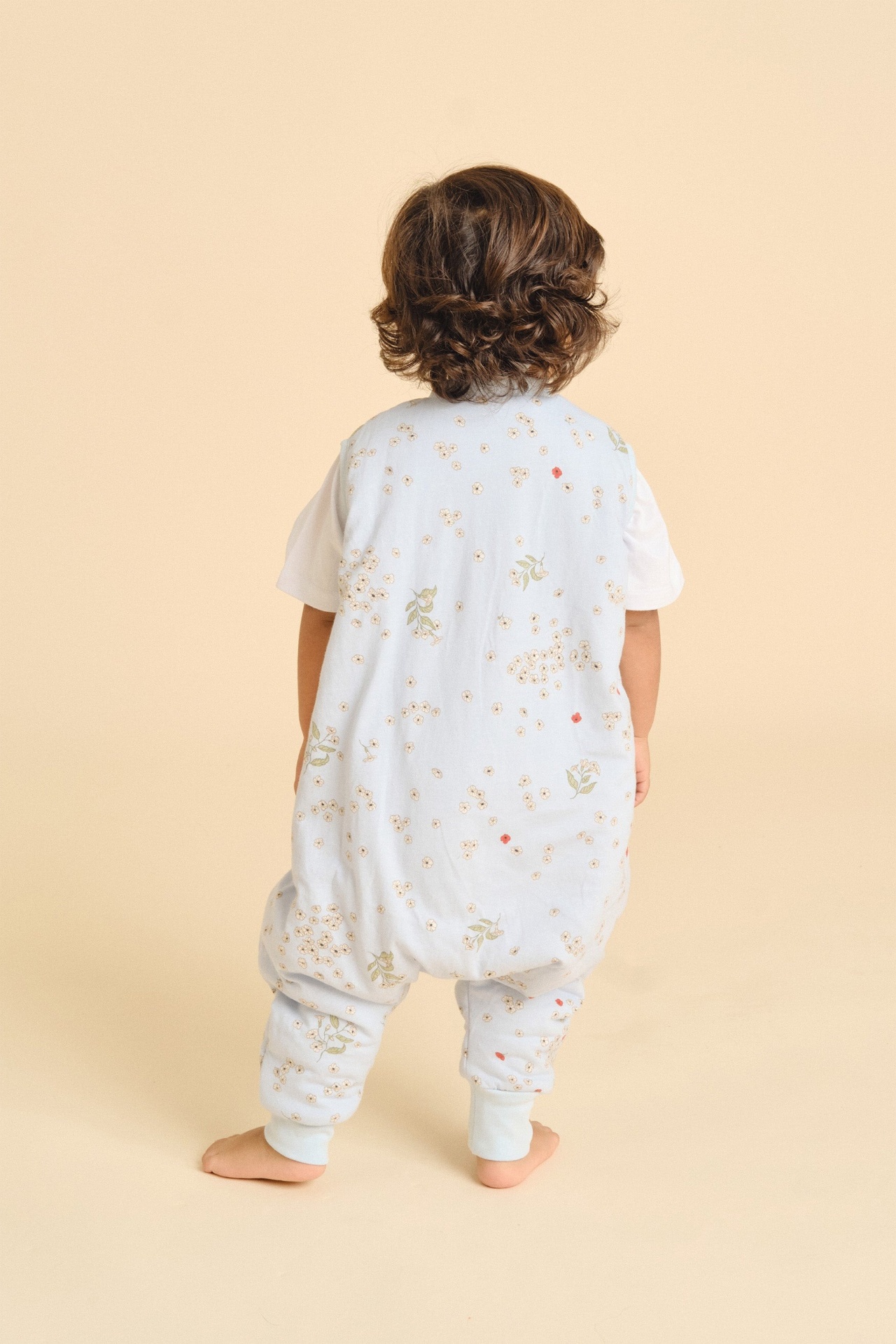 Criança de costas com fato de dormir azul claro floral e camiseta branca