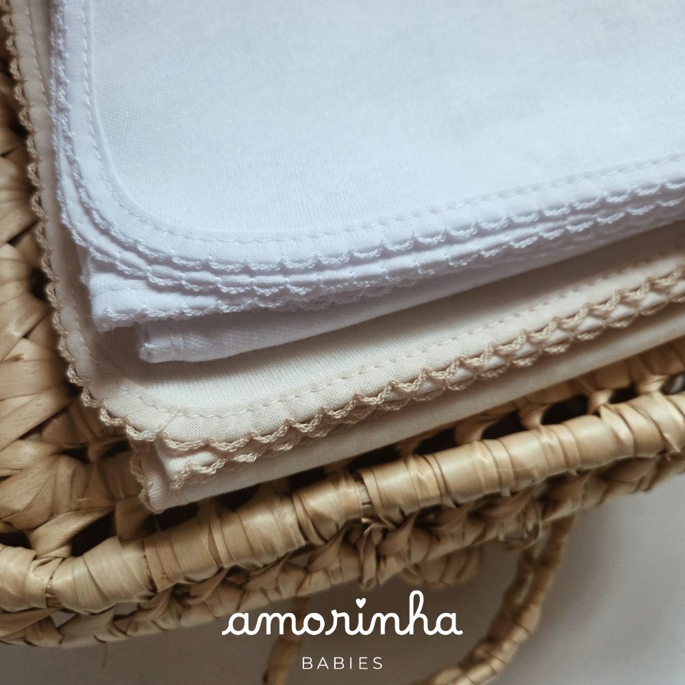 Paninhos de algodão branco e bege com bordado em renda numa cesta de vime